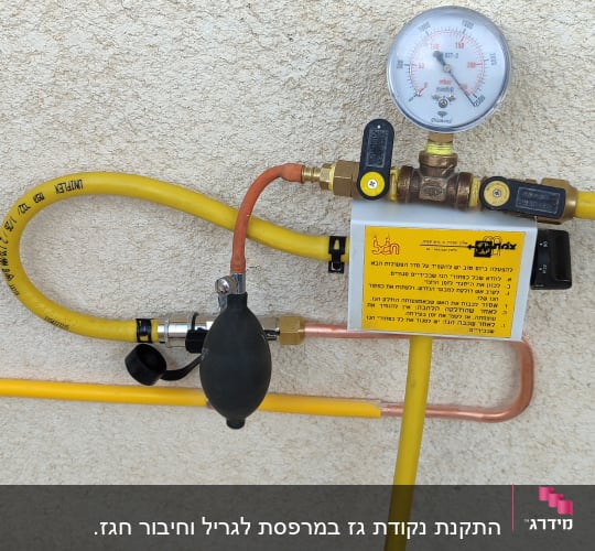 מד לחץ גז עם צינורות צהובים על קיר